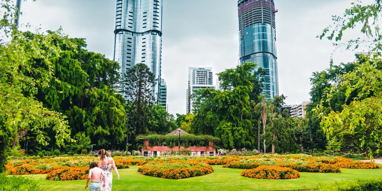 326449-a-mother-and-son-wander-through-the-city-botanic-gardens-with-skyscrapers-in-the-background-web-1280px