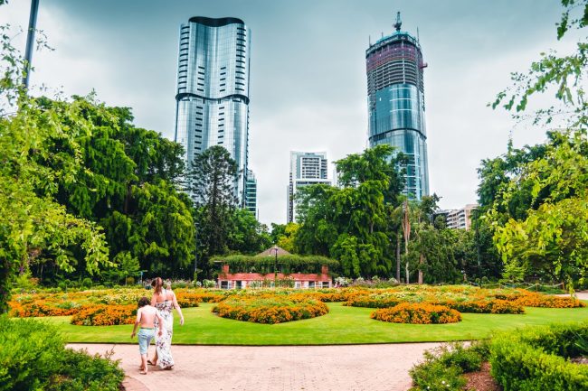 326449-a-mother-and-son-wander-through-the-city-botanic-gardens-with-skyscrapers-in-the-background-web-1280px