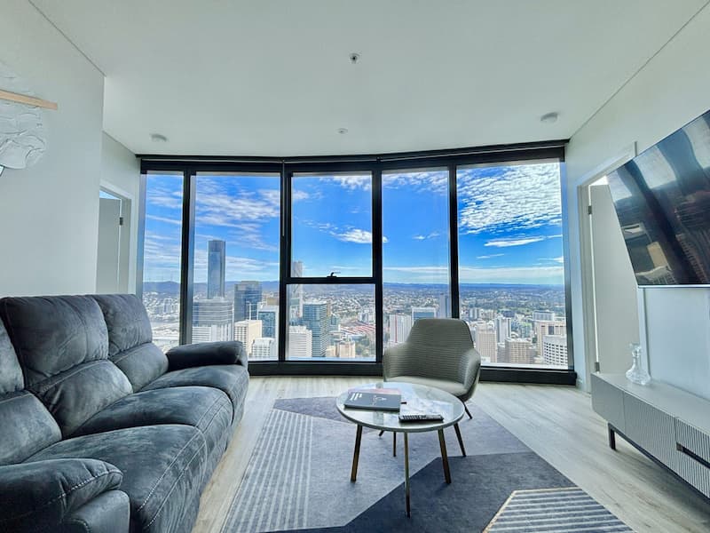 Inside the Brisbane Sky Tower luxury apartment on the 61st floor with panoramic city views, modern furnishings, and floor-to-ceiling windows